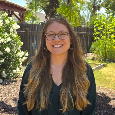 Outdoor portrait of a smiling woman with glasses and long ombre hair