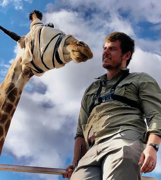 Calvin Price standing with blindfolded giraffe
