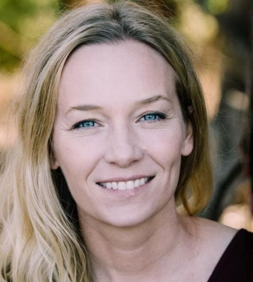 Smiling blonde woman headshot outdoors, soft blurred background