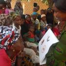 Guinean women looking at a bat safety book at a community outreach event 