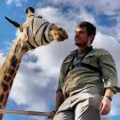 Calvin Price standing with blindfolded giraffe